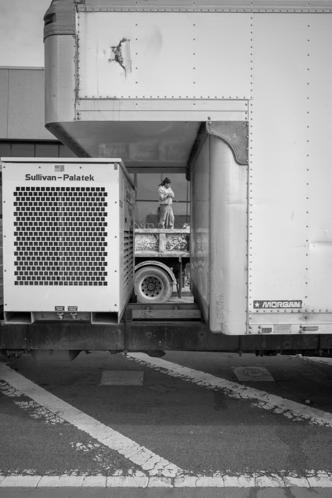 A curbside compressor and utility equipment sit inside a stark loading-bay frame.
