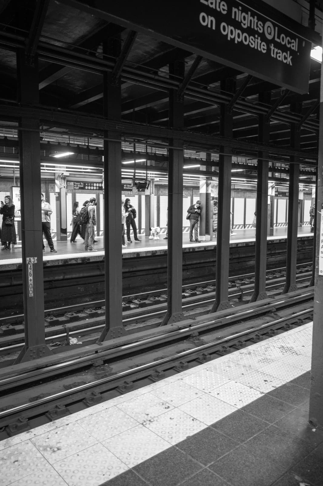 Commuters wait across the tracks on a New York subway platform.