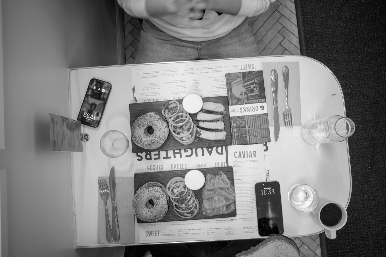 Coffee, plates, menus, and a compact camera fill an overhead breakfast table.