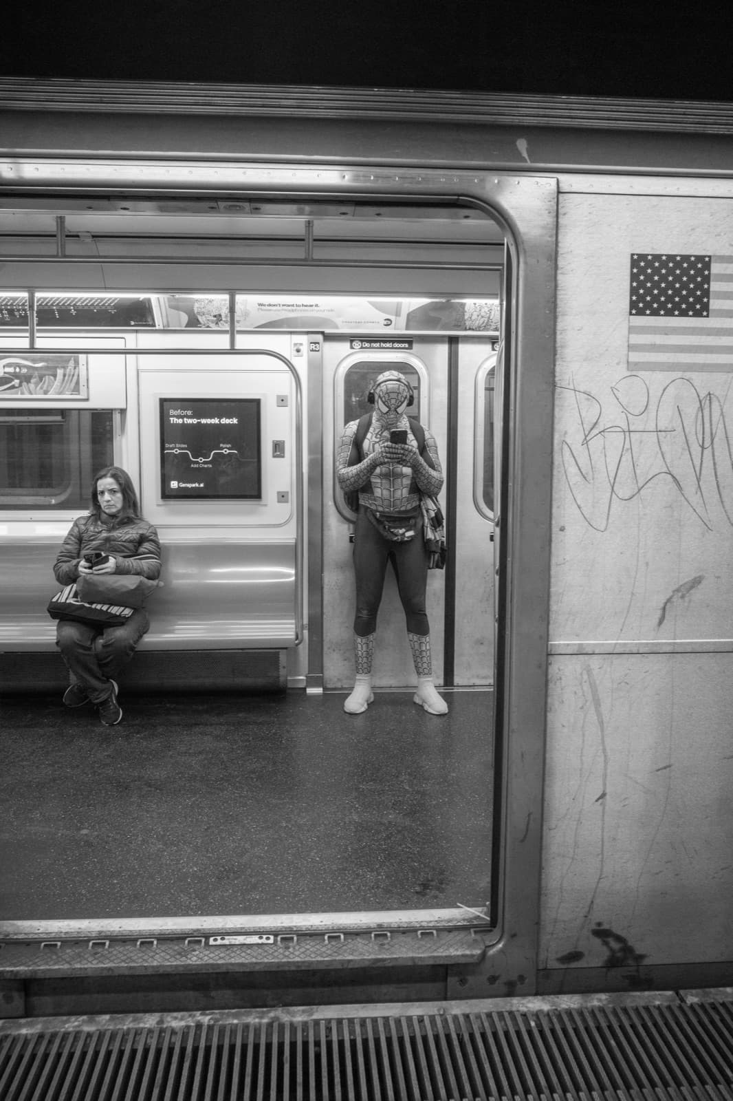 Two passengers are framed across the open doors of a New York subway car.