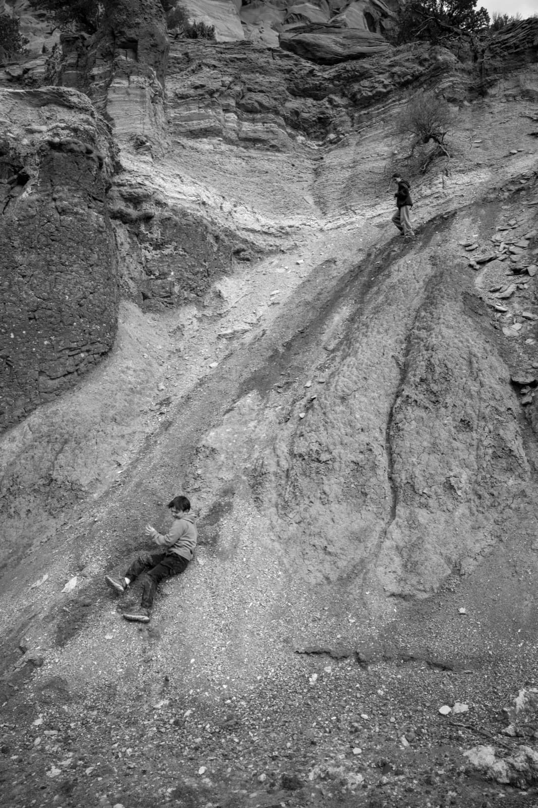 A tiny off-road vehicle follows a pale track through a vast rock basin.