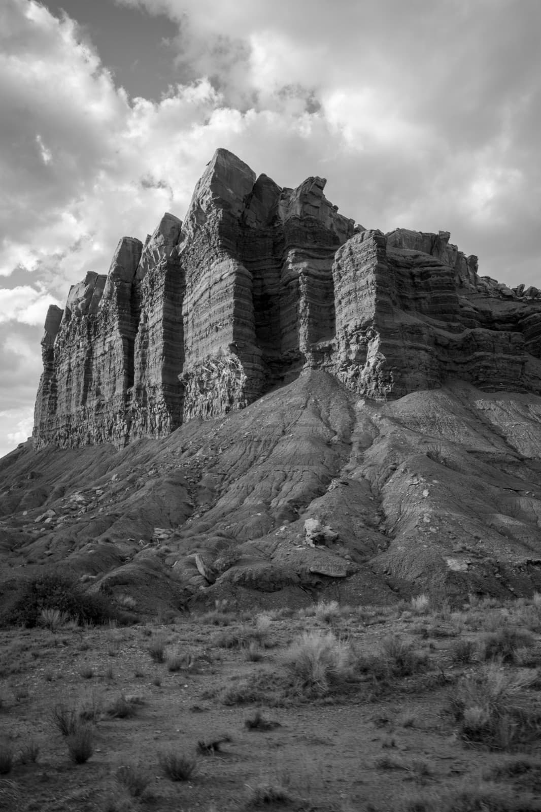 A monumental striated rock formation rises beneath dense clouds.