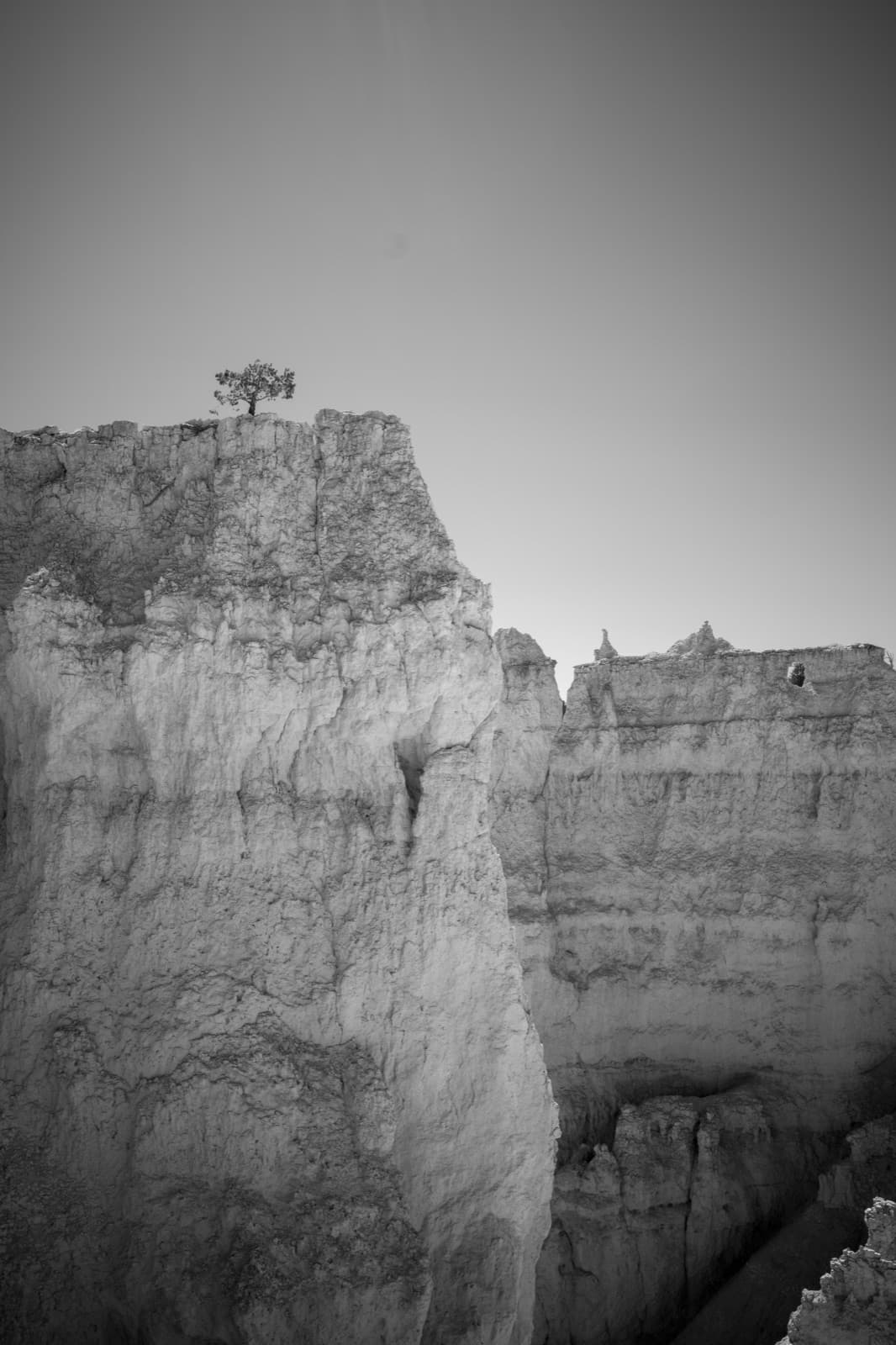 A bright eroded cliff edge rises into an open sky in black and white.